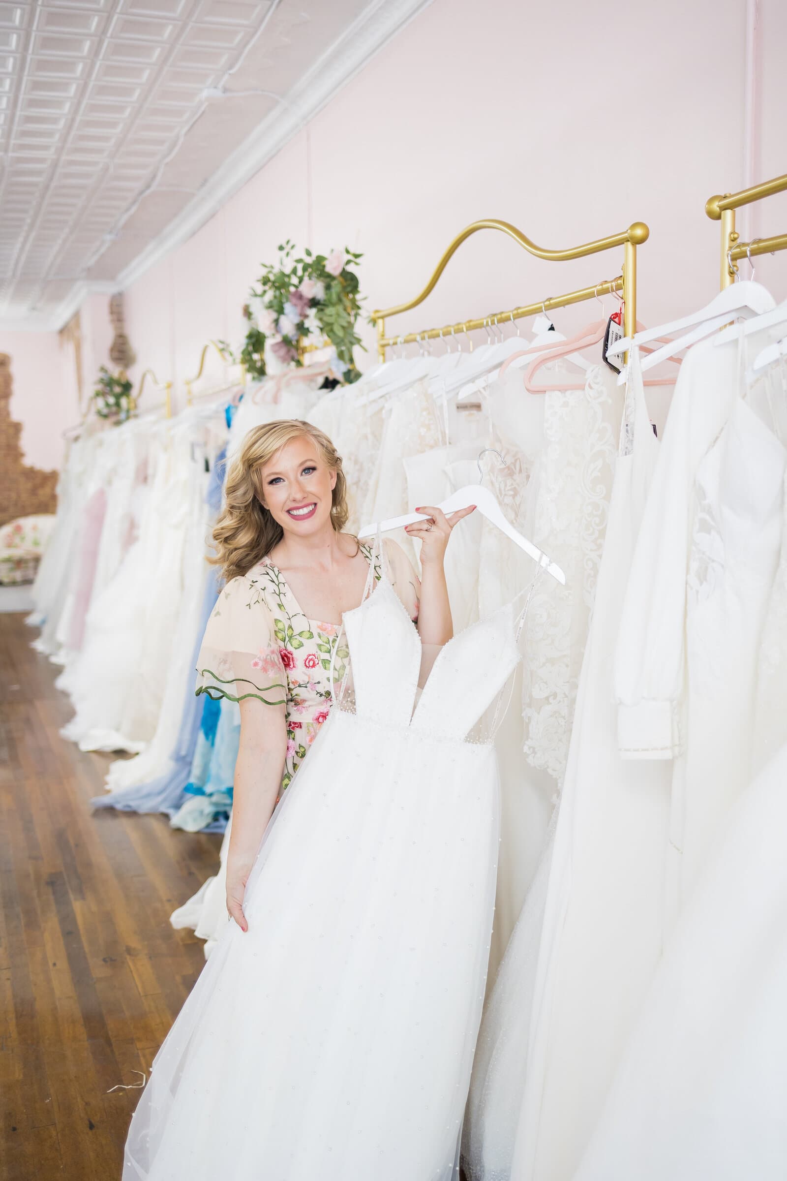 Kaitlyn, owner of Bride of the Pines, holding a gown in the boutique