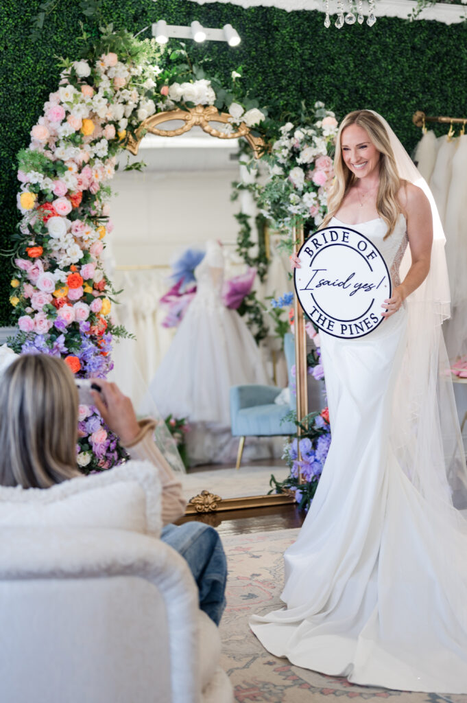 bride holding the I said yes at bride of the pines sign after saying yes to her wedding dress in pinehurst and southern pines nc